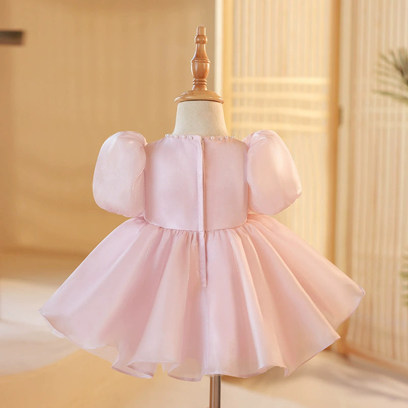 ✨ Descrizione del Vestito Rosa:

Un abito da principessa elegante e delicato in un rosa cipria incantevole, realizzato in organza, una tela trasparente e luminosa che conferisce un tocco di magia e raffinatezza al look. Questa stoffa è perfetta per creare volume grazie ai suoi plissettati verticali, che fanno sì che l'abito fluttui in modo etereo. La parte inferiore del vestito è arricchita da due fiocchi in organza a forma di rosa con perle, che aggiungono un dettaglio sofisticato e prezioso.

🌸 Caratteri