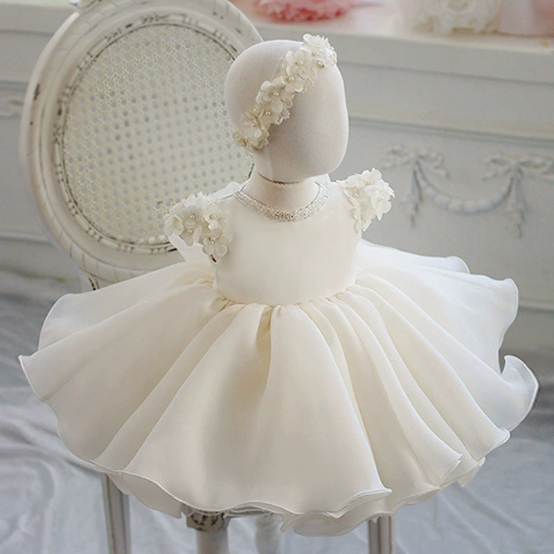👗 Vestito da principessa bianco con fiori e perle – Eleganza e volume scenografico

✨ Descrizione dell'immagine:
Questo splendido abito da principessa cattura l’attenzione con la sua gonna voluminosa in tulle, sollevata delicatamente dalle numerose stratificazioni che creano un effetto maestoso e fiabesco. Le maniche corte sono un dettaglio raffinato, realizzate con delicati fiori bianchi, ciascuno decorato con una perla centrale, donando un tocco di romanticismo e grazia. Il colletto gioiello, simile a un
